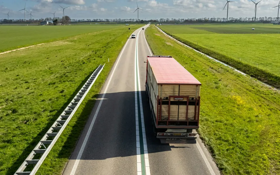 Lastwagen auf einer Landstraße zwischen Feldern